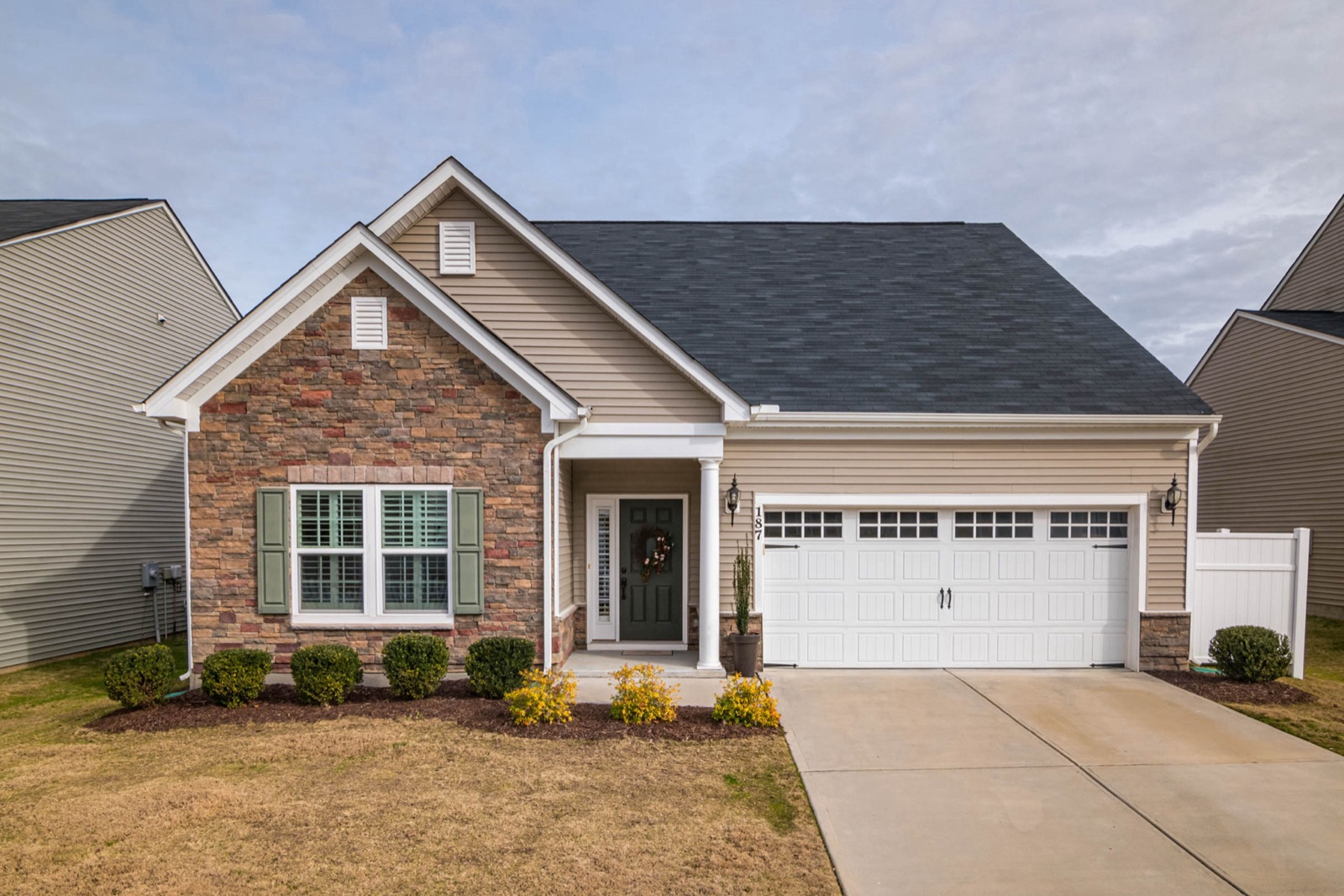 A brick and siding house with a double garage under a grey sky